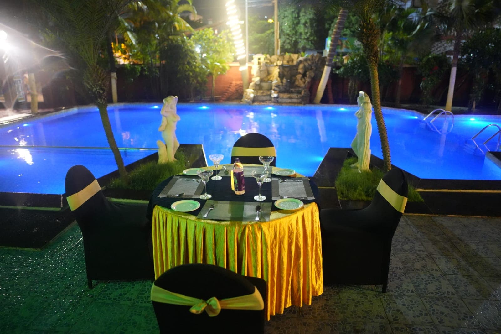 Night poolside dinner table with blue light pool